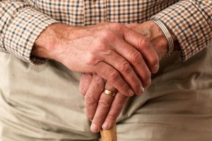 Older man resting his hands on a cane.