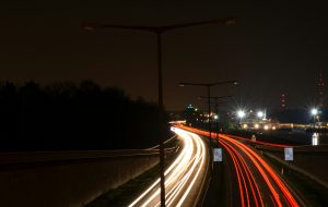 Time-lapse photo of street at night showing streaks of headlights and taillights