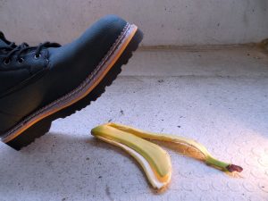 A booted foot about to step onto a banana peel