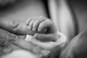 A baby's hand around an adult's finger