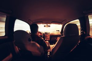 a man driving a car as viewed from the backseat