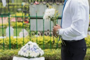 a man holding flowers near a grave