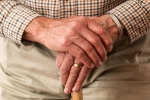 an elder's hands holding a cane