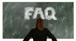 A man looking at letters "FAQ" on a chalkboard