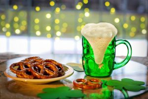 A green mug of beer and pretzels on a table