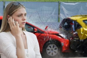 A woman on the phone in front of a car accident