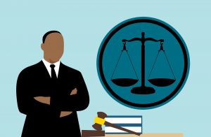 An illustration of a lawyer standing next to the scales of justice